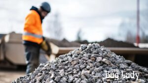 Gravel beside a worker inspecting the materials outdoors.